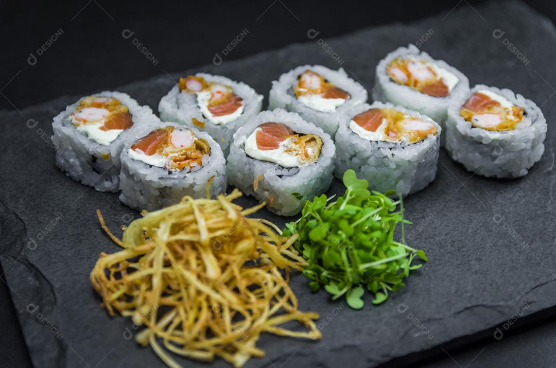 Sushi, cozinha tradicional japonesa. Delicioso Uramaki na placa decorada, fundo preto.