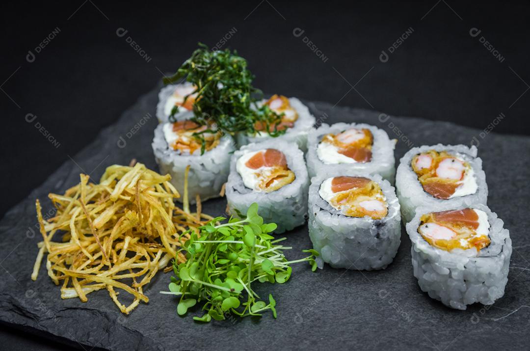 Sushi, cozinha tradicional japonesa. Delicioso Uramaki na placa decorada, fundo preto.