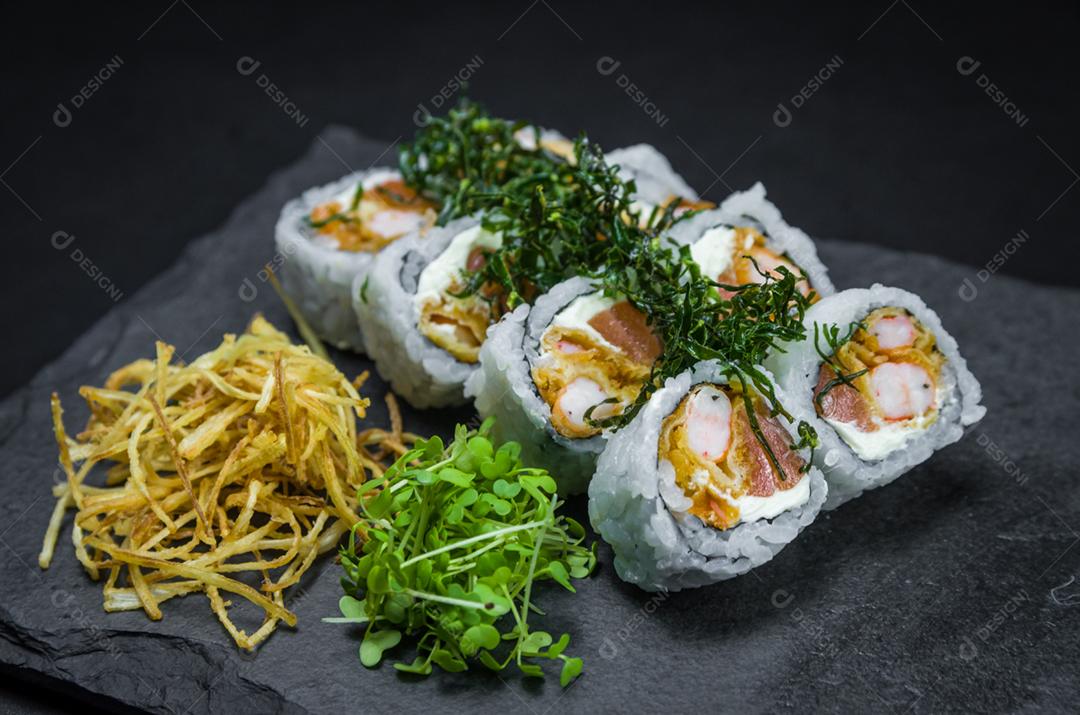 Sushi, cozinha tradicional japonesa. Delicioso Uramaki na placa decorada, fundo preto.
