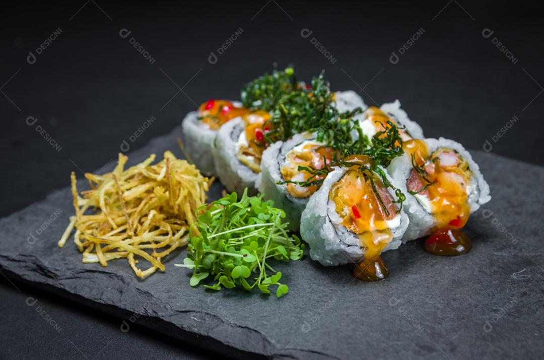 Sushi, cozinha tradicional japonesa. Delicioso Uramaki na placa decorada, fundo preto.