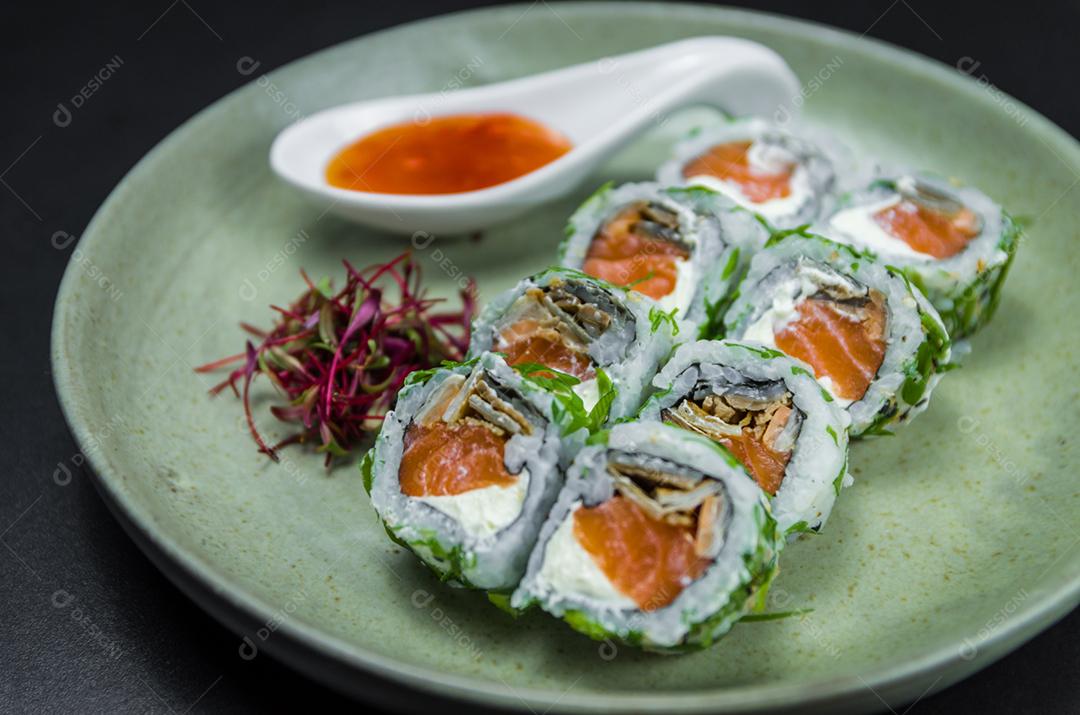 Sushi perfeito, cozinha tradicional japonesa. Delicioso uramaki com molho agridoce no prato decorado