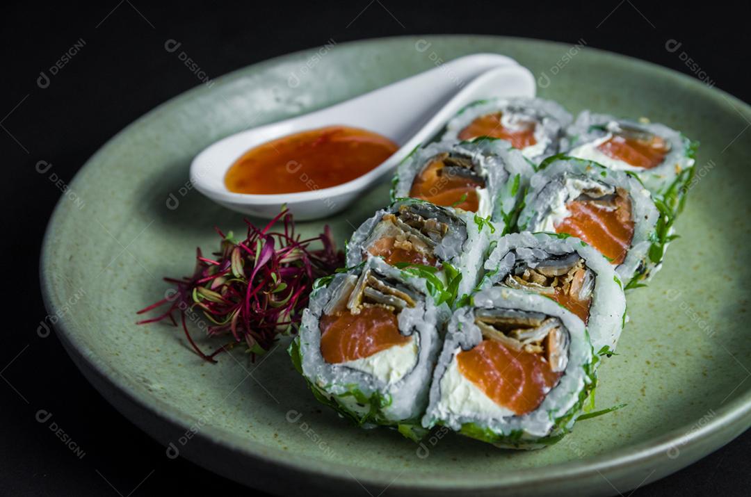 Sushi perfeito, cozinha tradicional japonesa. Delicioso uramaki com molho agridoce no prato decorado