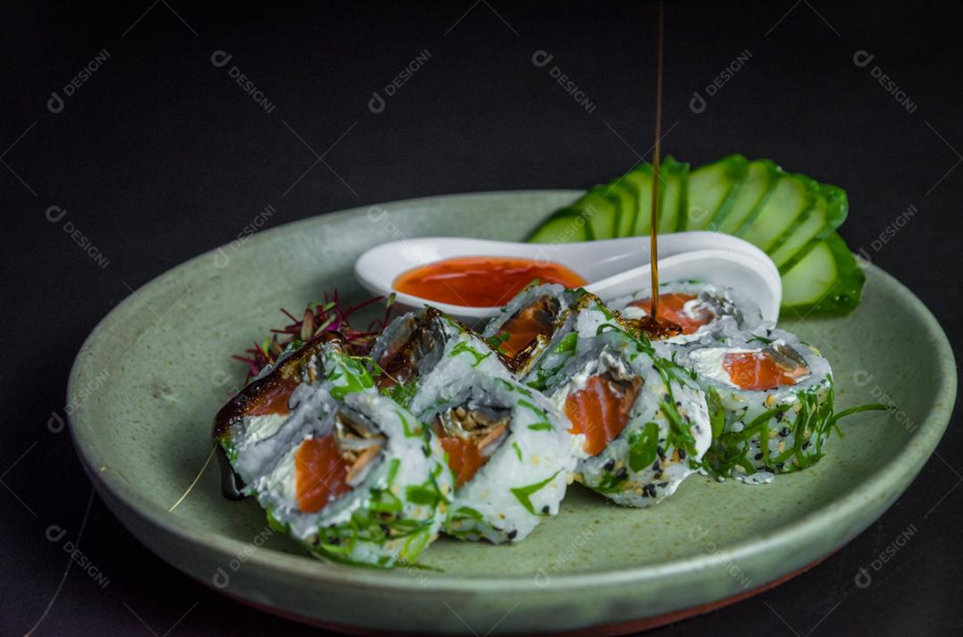 Sushi perfeito, cozinha tradicional japonesa. Delicioso uramaki com molho agridoce no prato decorado
