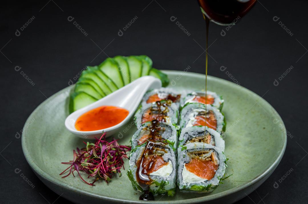 Sushi perfeito, cozinha tradicional japonesa. Delicioso uramaki com molho agridoce no prato decorado