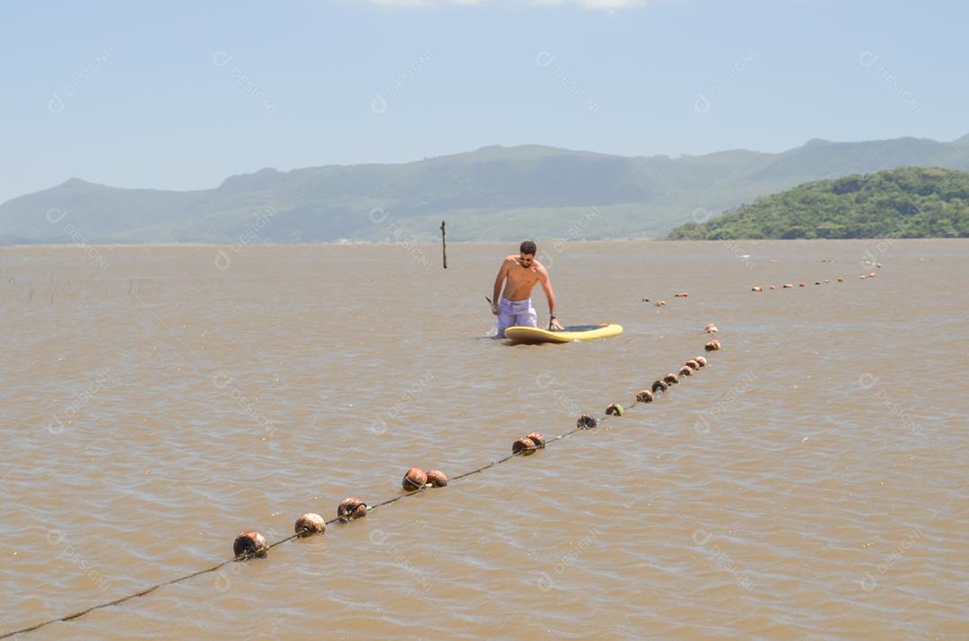 Young man practicing Stand Up Paddle on the lake, yellow board, paddling. Paddleboard.