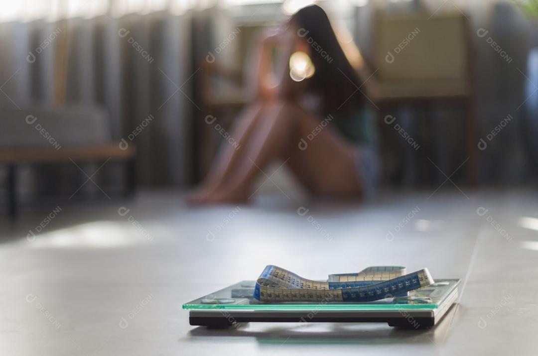 Conceito de falha na perda de peso, escala em primeiro plano e mulher frustrada frustrada em segundo plano.