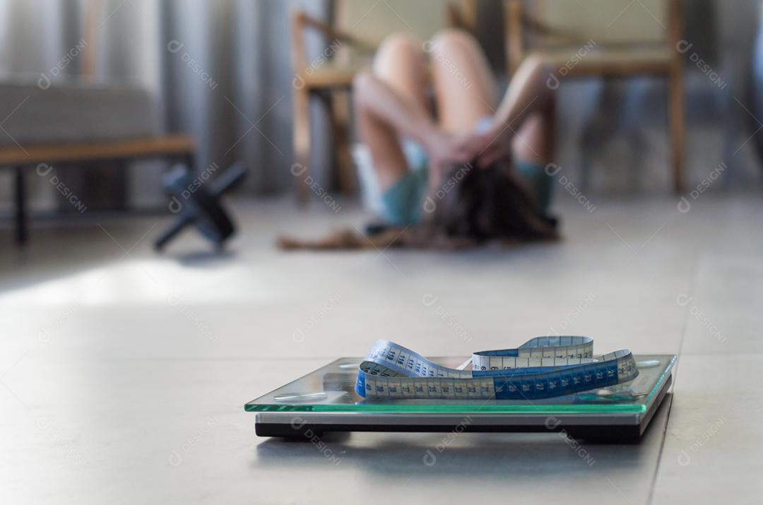 Conceito de falha na perda de peso, escala em primeiro plano e mulher frustrada frustrada em segundo plano.