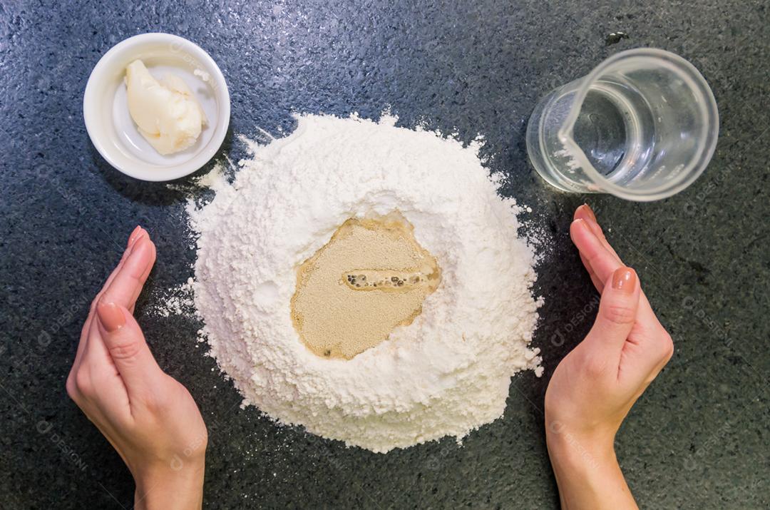 Mulher preparando massa de pizza na mesa de granito preto