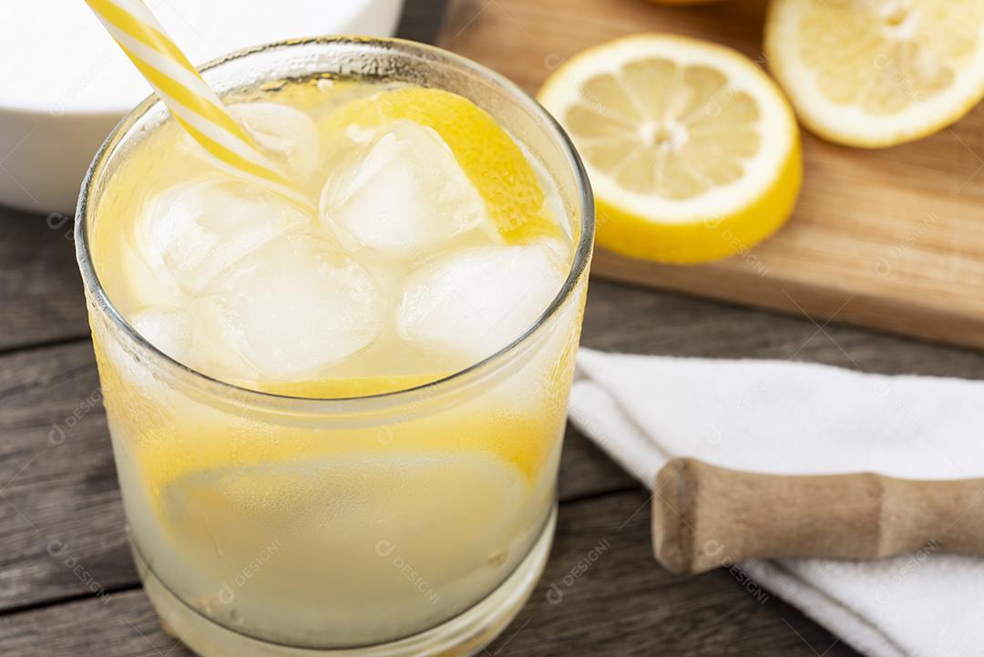 Caipirinha de limão siciliano brasileiro em um copo com gelo com fatias de frutas sobre tábua de madeira .