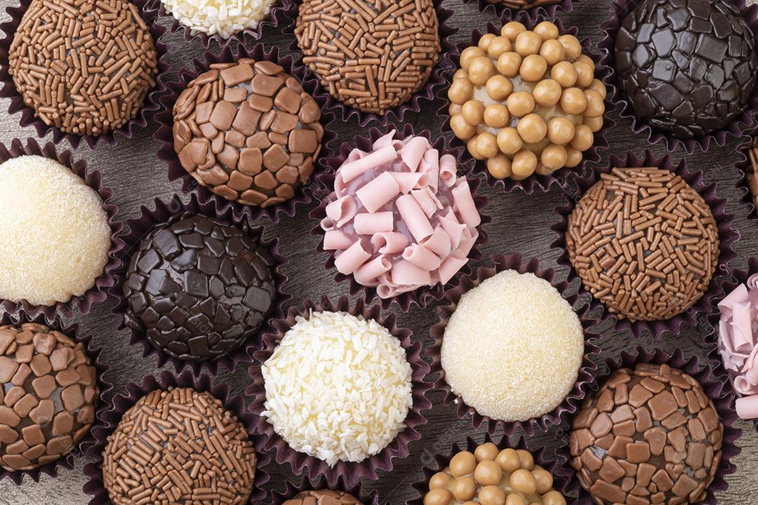 Brigadeiros típicos brasileiros, vários sabores sobre mesa de madeira.