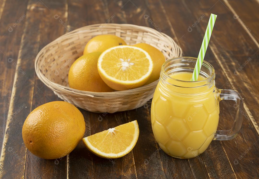 Suco de laranja com laranja fatiada sobre uma mesa de madeira.