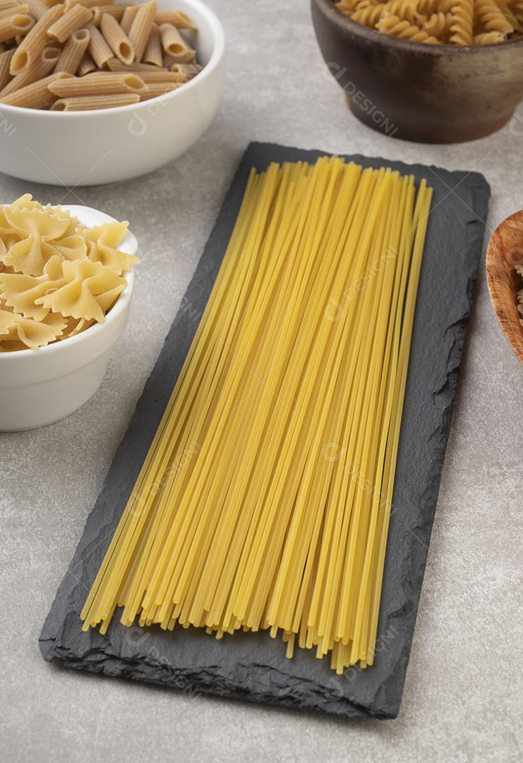 Espaguete, farfalle, fusilli e macarrão penne sobre bancada de concreto.