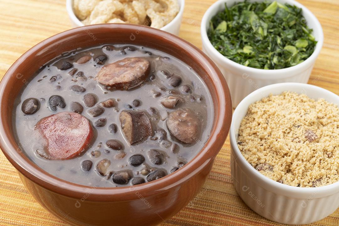 Tradicional feijoada brasileira com laranja, couve e farinha de mandioca.