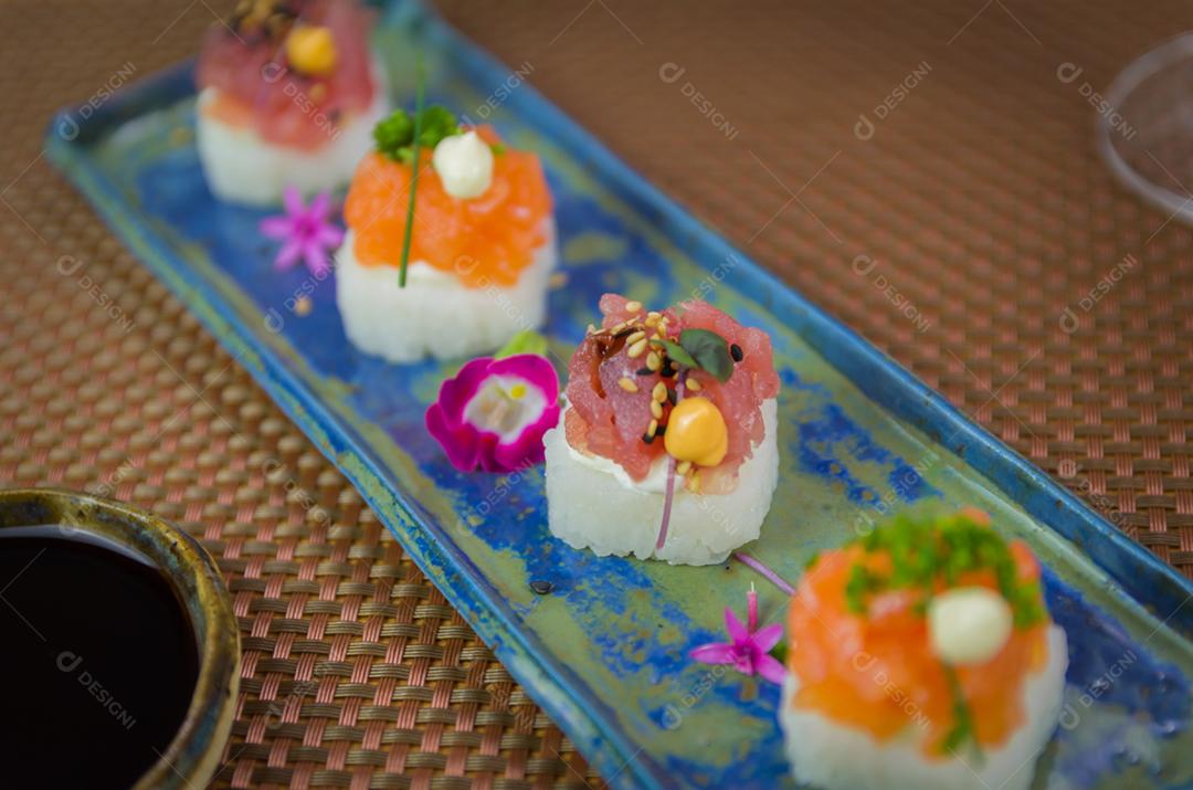 Delicioso sushi premium de salmão e atum Oshizushi em um prato de porcelana artesanal decorado.