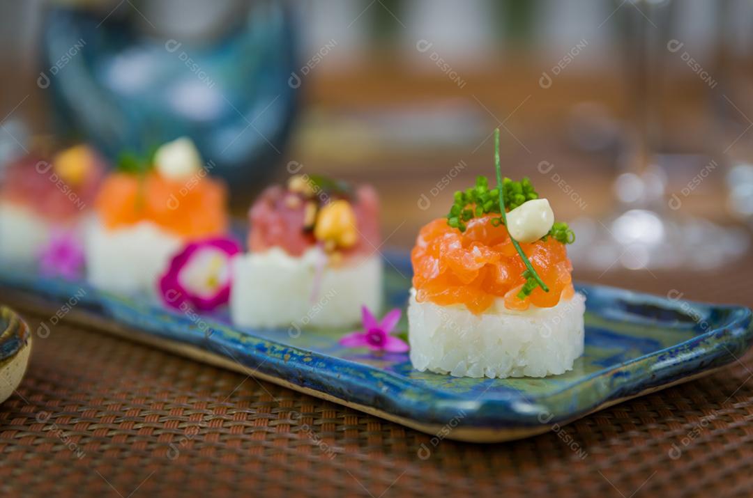 Delicioso sushi premium de salmão e atum Oshizushi em um prato de porcelana artesanal decorado.