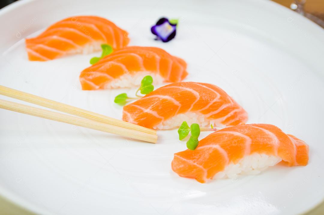 Delicioso nigiri de salmão premium na chapa branca artesanal decorada com flores comestíveis.