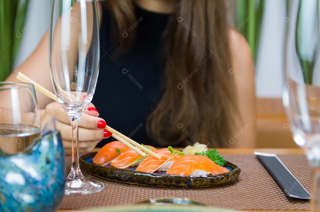 Mulher comendo sushi delicioso, closeup em pauzinhos