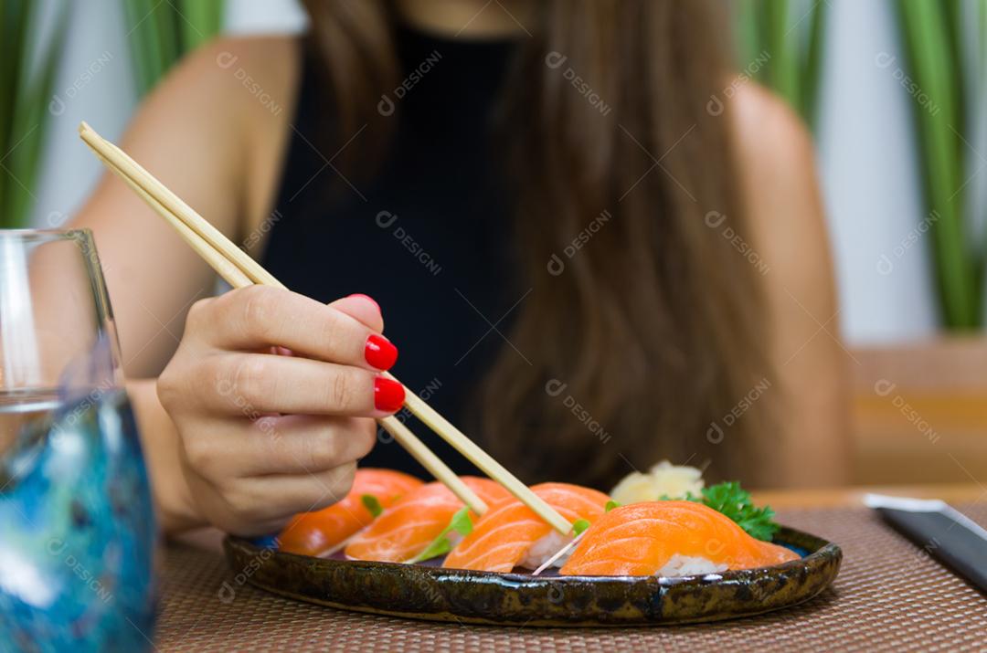 Mulher comendo sushi delicioso, closeup em pauzinhos