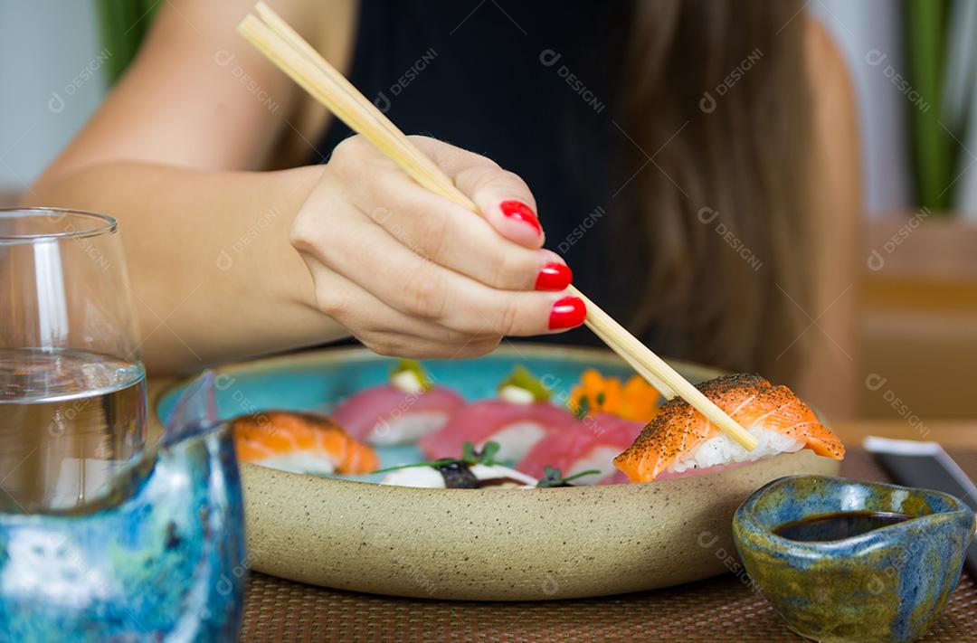 Mulher comendo sushi delicioso, closeup em pauzinhos.