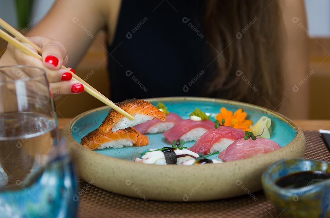 Mulher comendo sushi delicioso, closeup em pauzinhos.