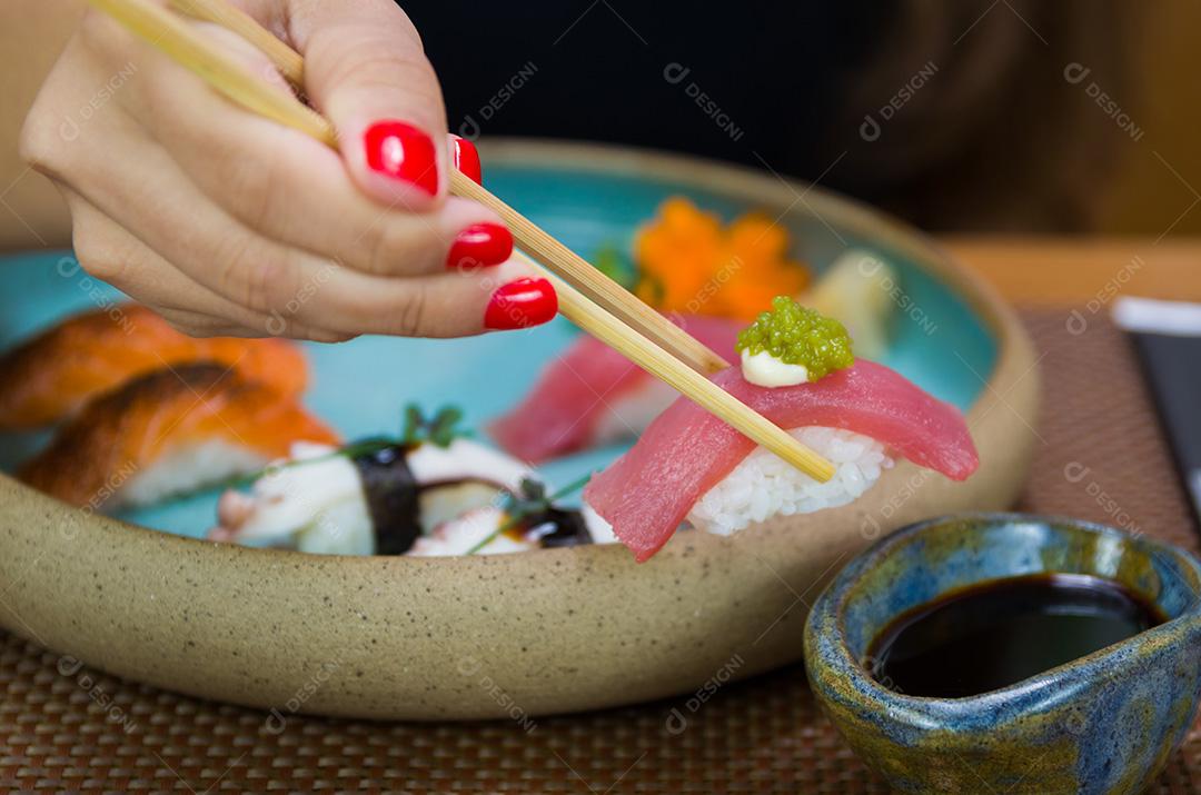 Mulher comendo sushi delicioso, closeup em pauzinhos.