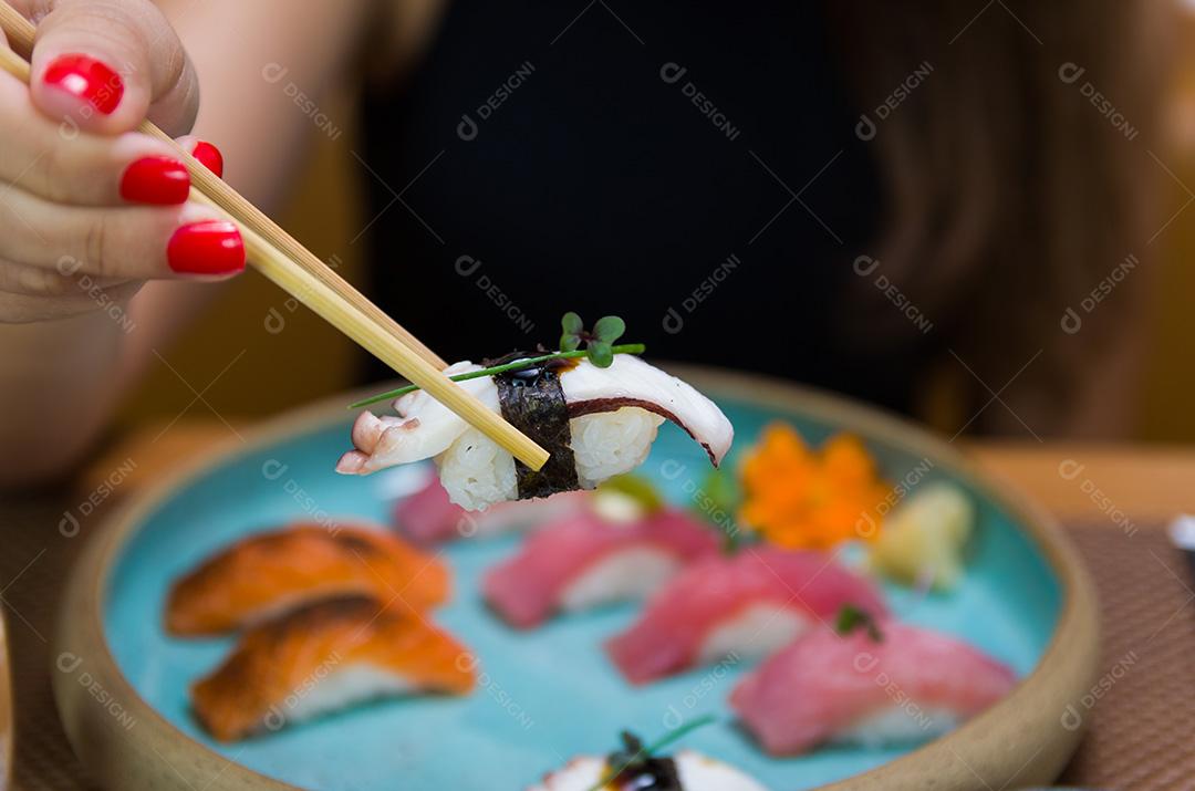 Mulher comendo sushi delicioso, closeup em pauzinhos.