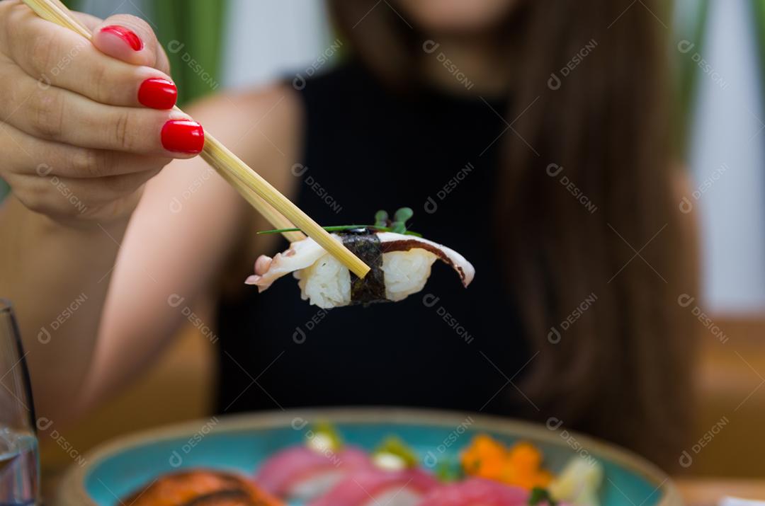 Mulher comendo sushi delicioso, closeup em pauzinhos