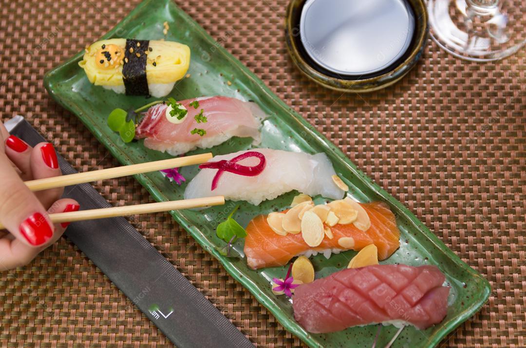 Prato com diferentes tipos de nigirizushi, nigiri com diferentes peixes e um decorado com símbolo de câncer de mama feminino