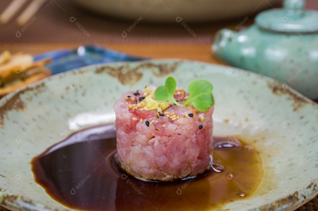 Homem derramando molho de soja em delícias de tártaro de atum em um lindo prato decorado.