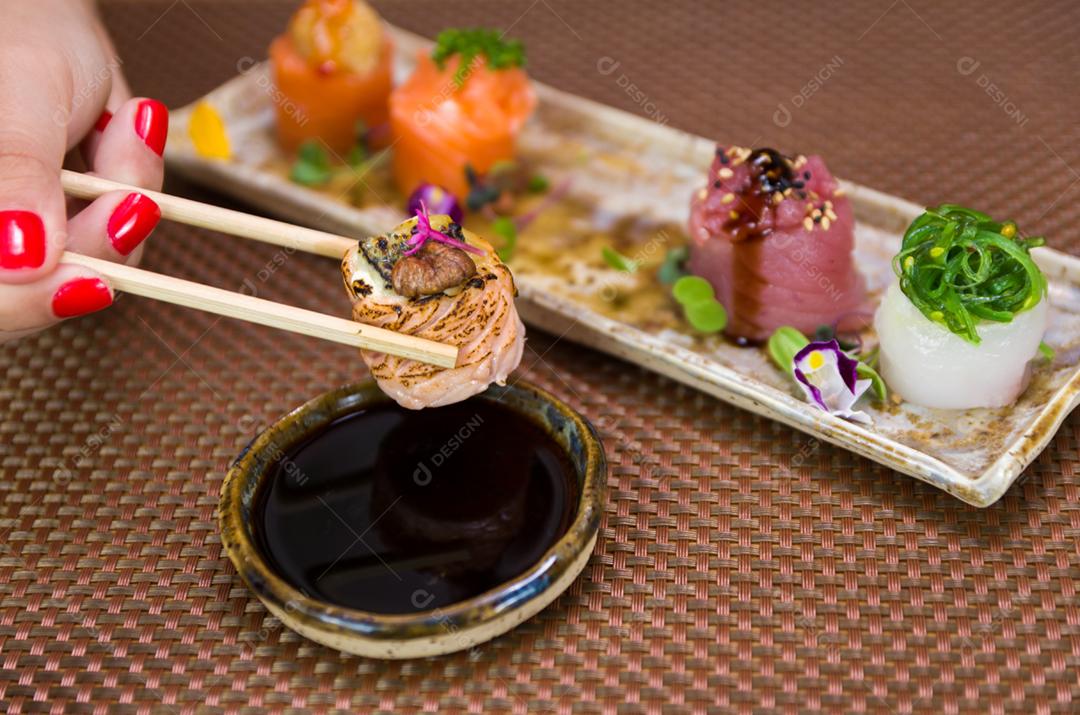 Mulher comendo delicioso sushi gunkan, closeup em pauzinhos