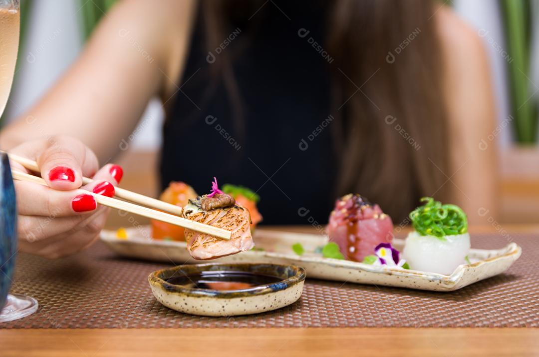 Mulher comendo delicioso sushi gunkan, closeup em pauzinhos