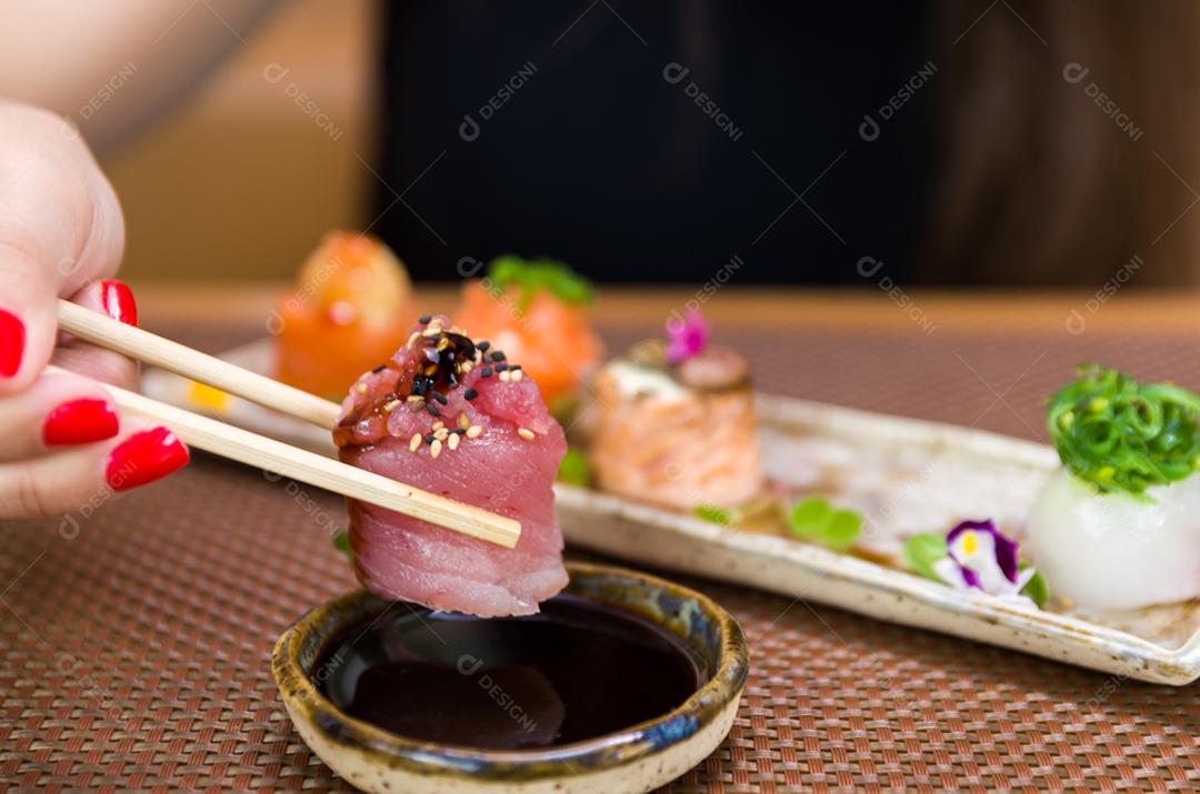 Mulher comendo delicioso sushi gunkan, closeup em pauzinhos