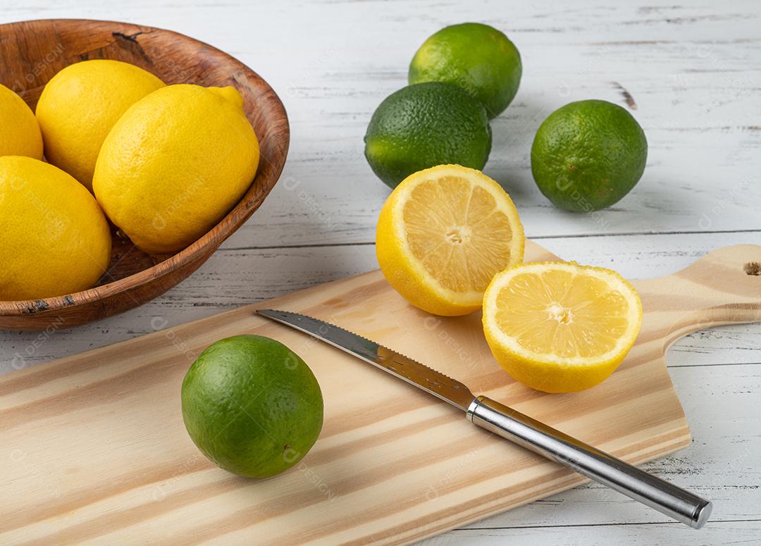 Laranja, limão verde e limão siciliano cortam sobre tábua de madeira.