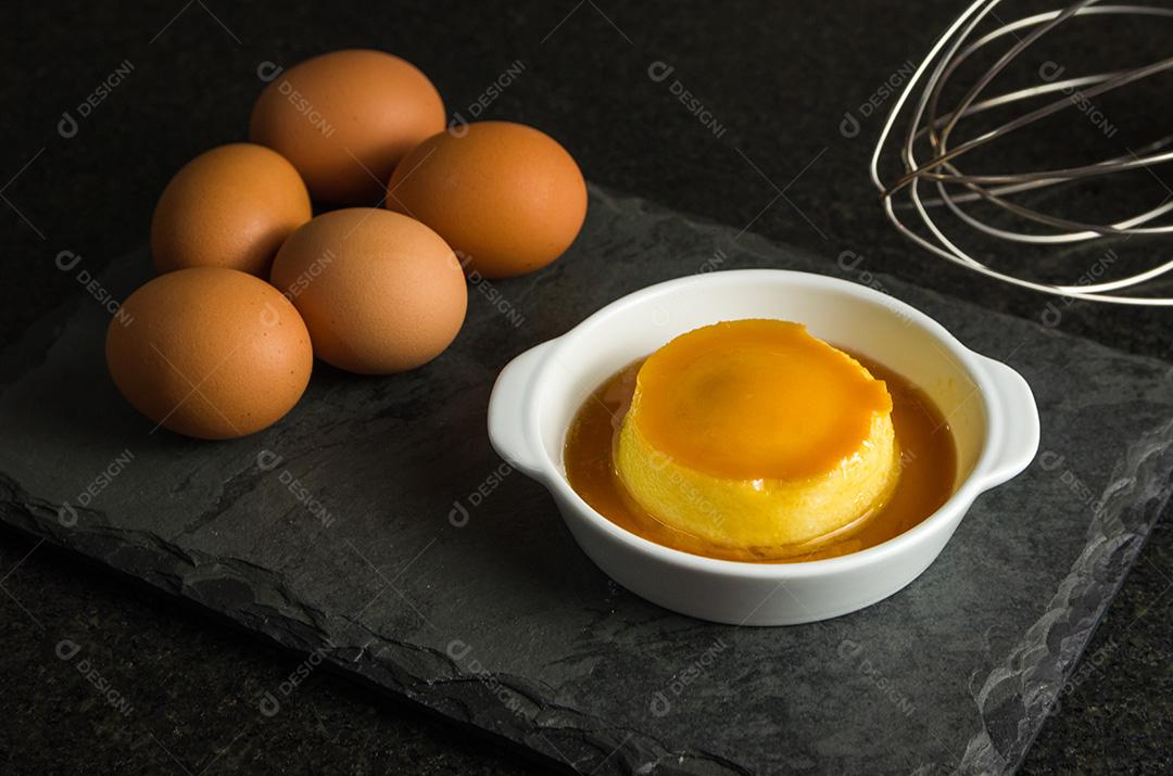 Sobremesa tradicional brasileira, pudim de leite em fundo escuro.