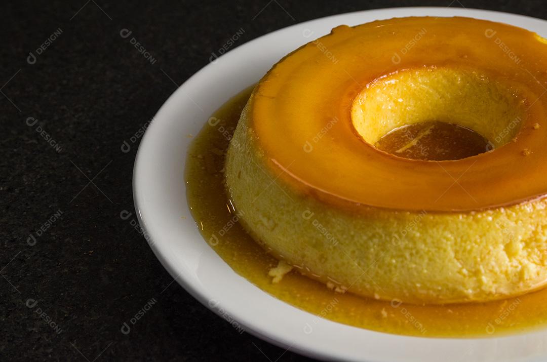 Sobremesa tradicional brasileira, pudim de leite em fundo escuro.