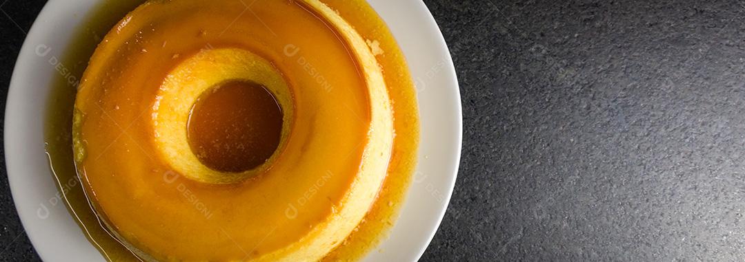 Sobremesa tradicional brasileira, pudim de leite em fundo escuro.