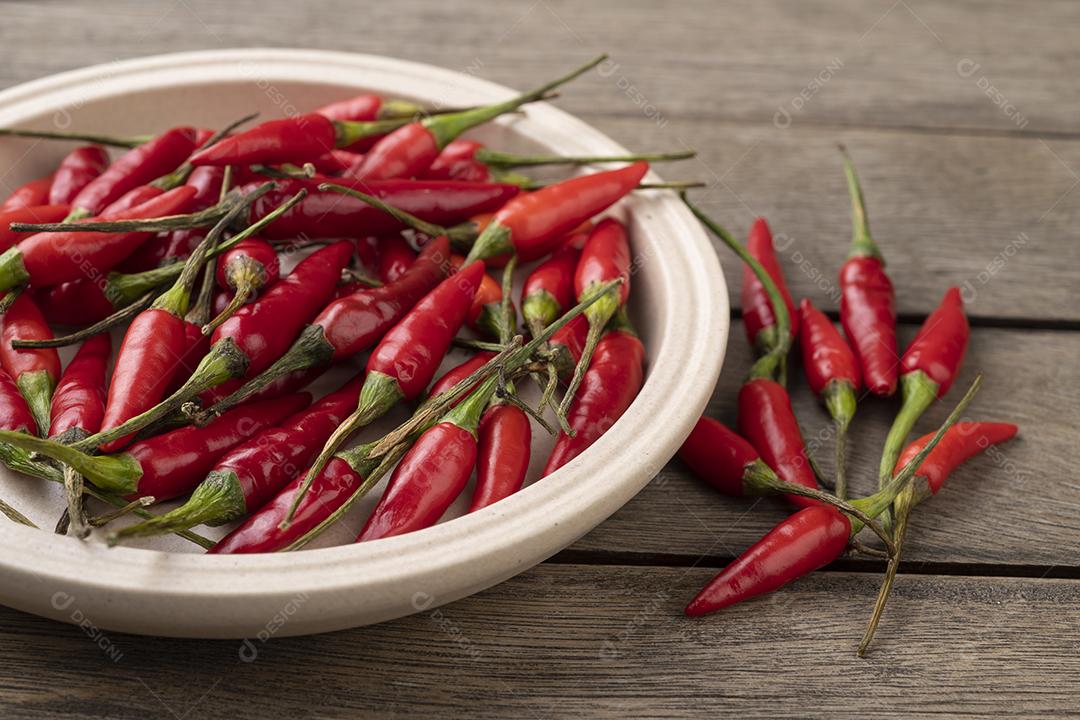 Pimentão vermelho malagueta em um prato sobre mesa de madeira.