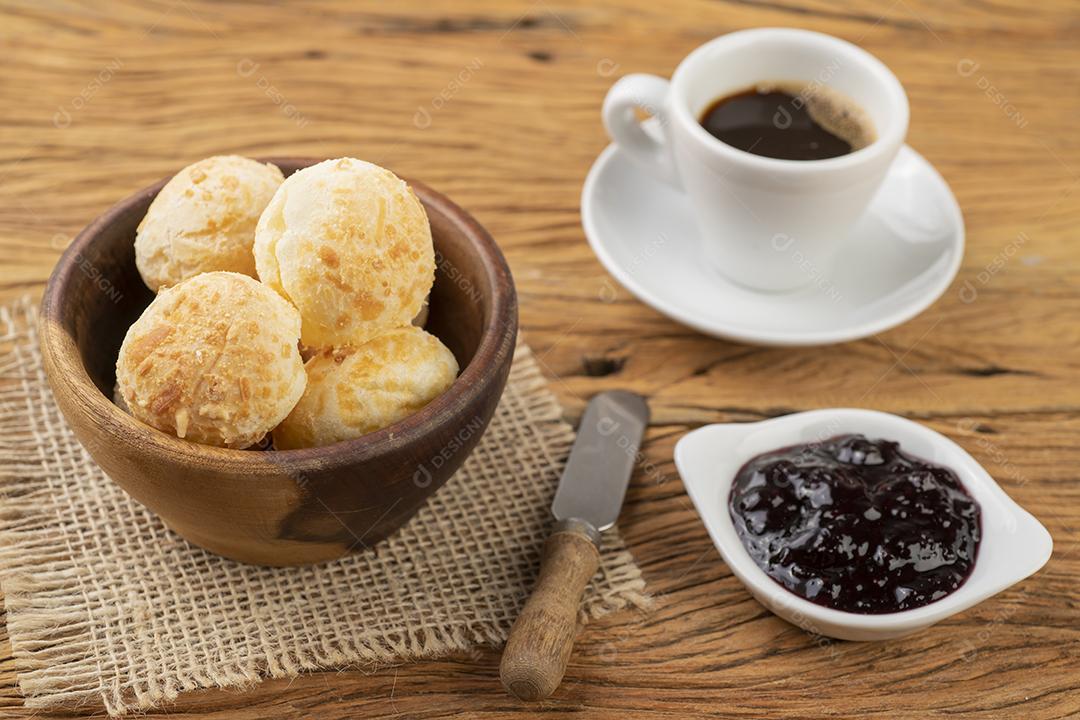 Típico pão de queijo brasileiro em uma cesta, café e geleia.