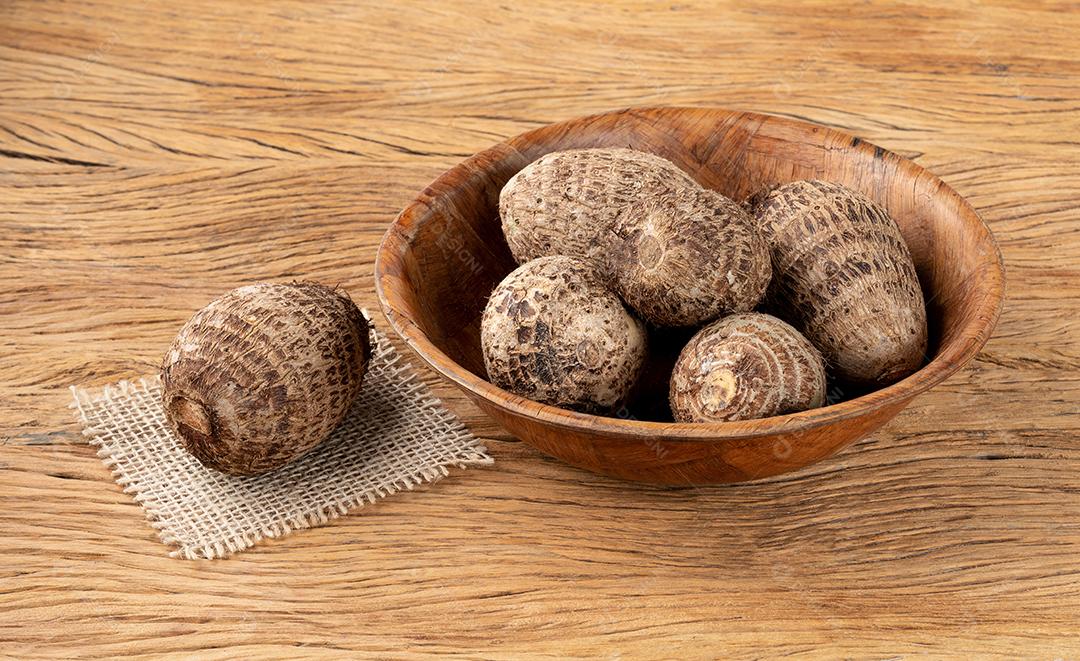 Inhame cru ou em jogos em uma tigela sobre mesa de madeira.