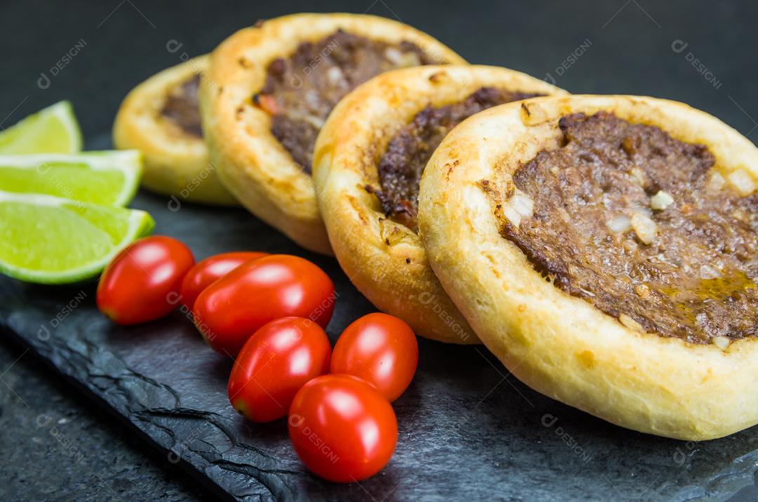 Deliciosa comida libanesa (árabe), esfihas genuínas em um prato de ardósia com tomates e limões.