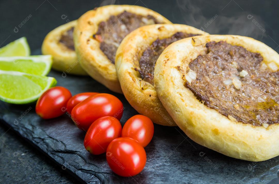 Deliciosa comida libanesa (árabe), esfihas genuínas em um prato de ardósia com tomates e limões.