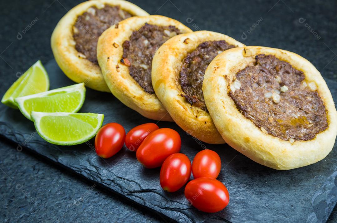 Deliciosa comida libanesa (árabe), esfihas genuínas em um prato de ardósia com tomates e limões.