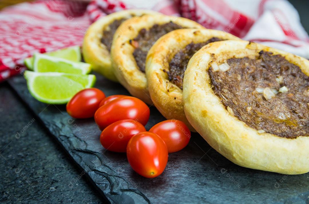 Deliciosa comida libanesa (árabe), esfihas genuínas em um prato de ardósia com tomates e limões