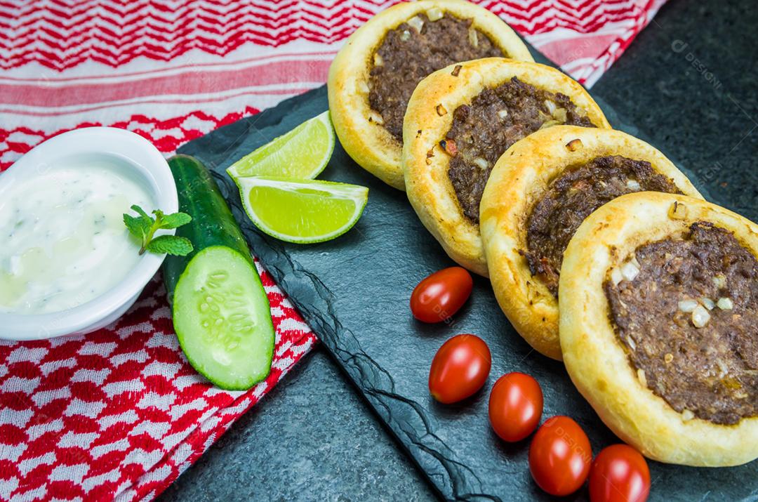 Deliciosa comida libanesa (árabe), esfihas genuínas em uma placa de ardósia com tomates, limões