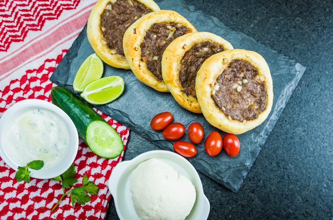 Deliciosa comida libanesa (árabe), esfihas genuínas em uma placa de ardósia com tomates, limões