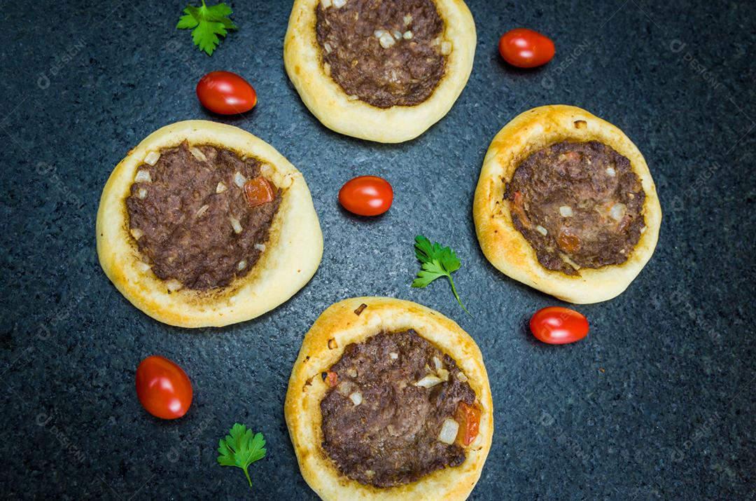 Deliciosa comida libanesa (árabe), esfihas legítimas em um fundo de granito preto com tomates, limões.