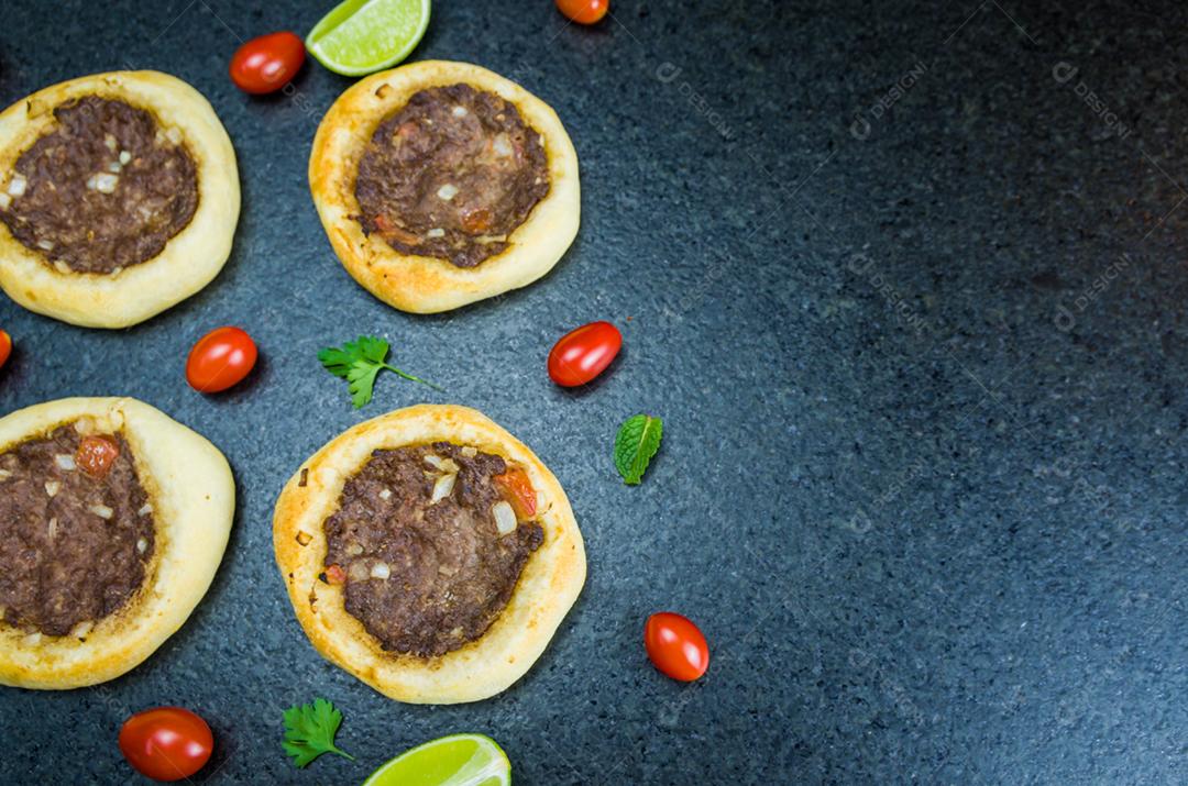 Deliciosa comida libanesa (árabe), esfihas legítimas em um fundo de granito preto com tomates, limões.