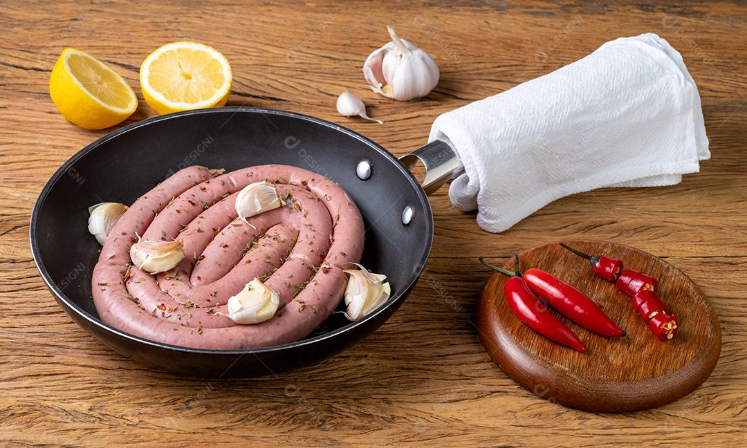 Salsicha de porco crua em uma panela com limão siciliano e temperos.