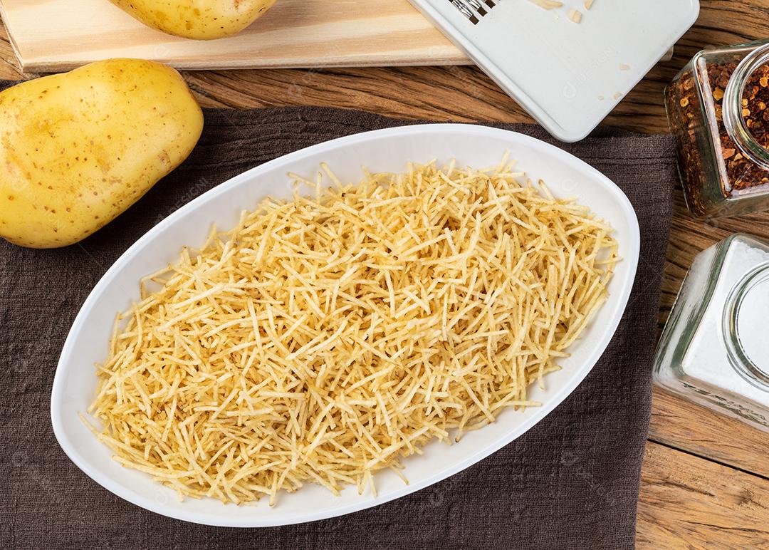 Batata palha ou batata palha em um prato branco com batatas cruas.