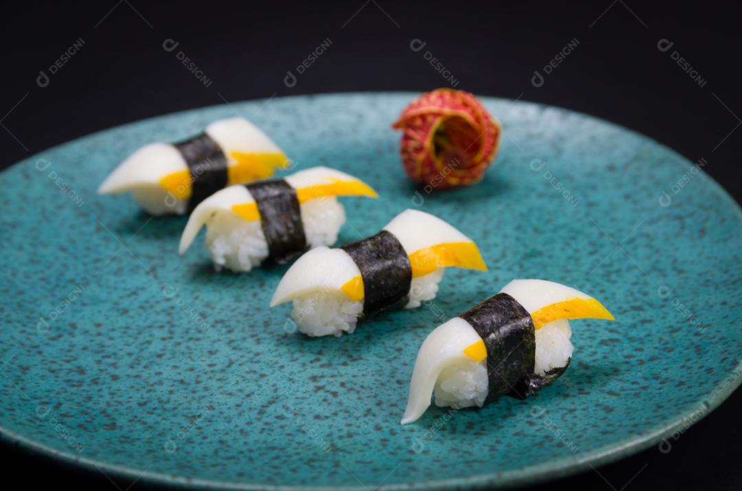 Sushi, cozinha tradicional japonesa. Delicioso sushi Hadock Tako na placa decorada, fundo preto.